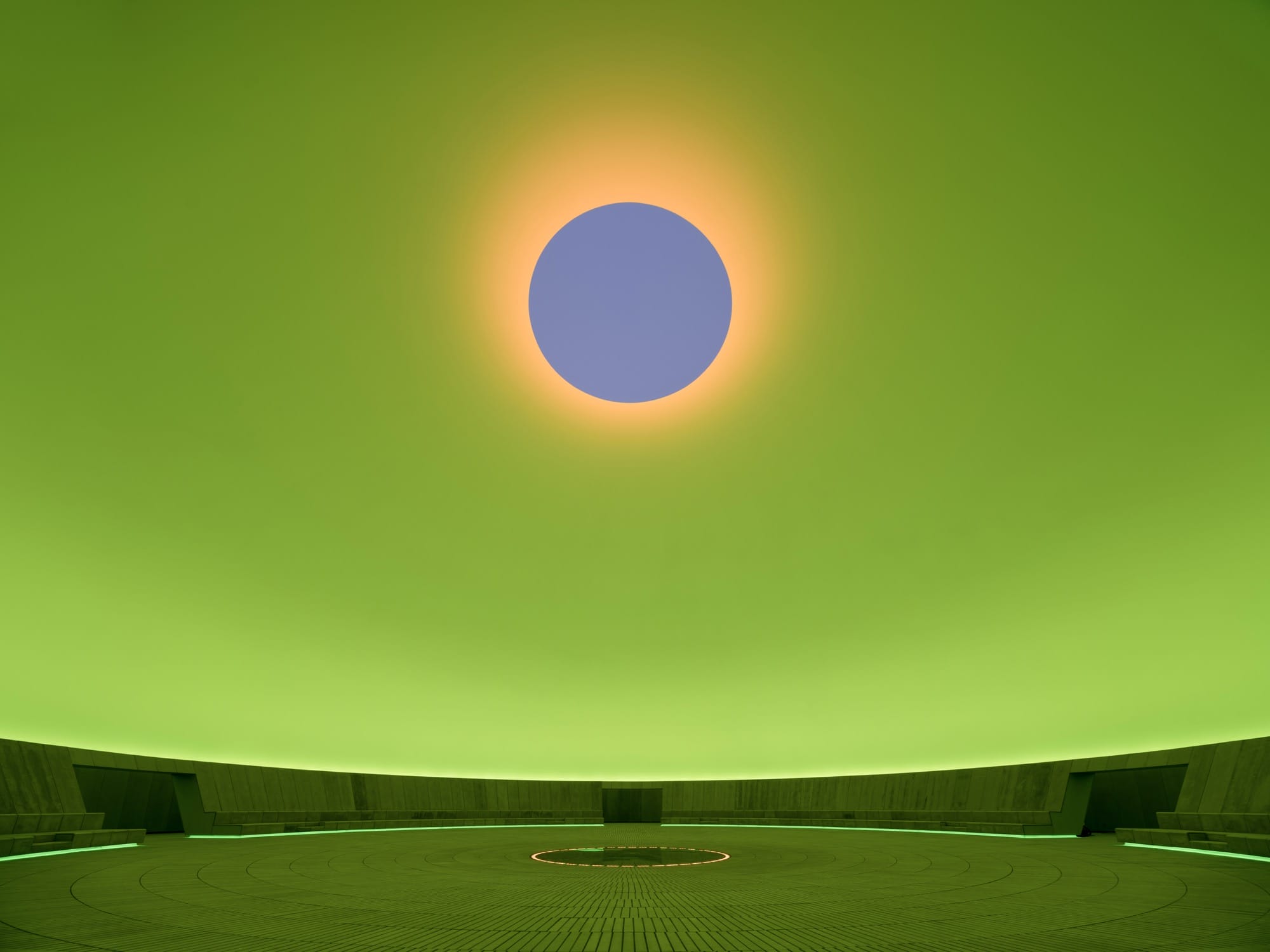 A large-scale light installation by James Turrell with a gray oculus in a green dome