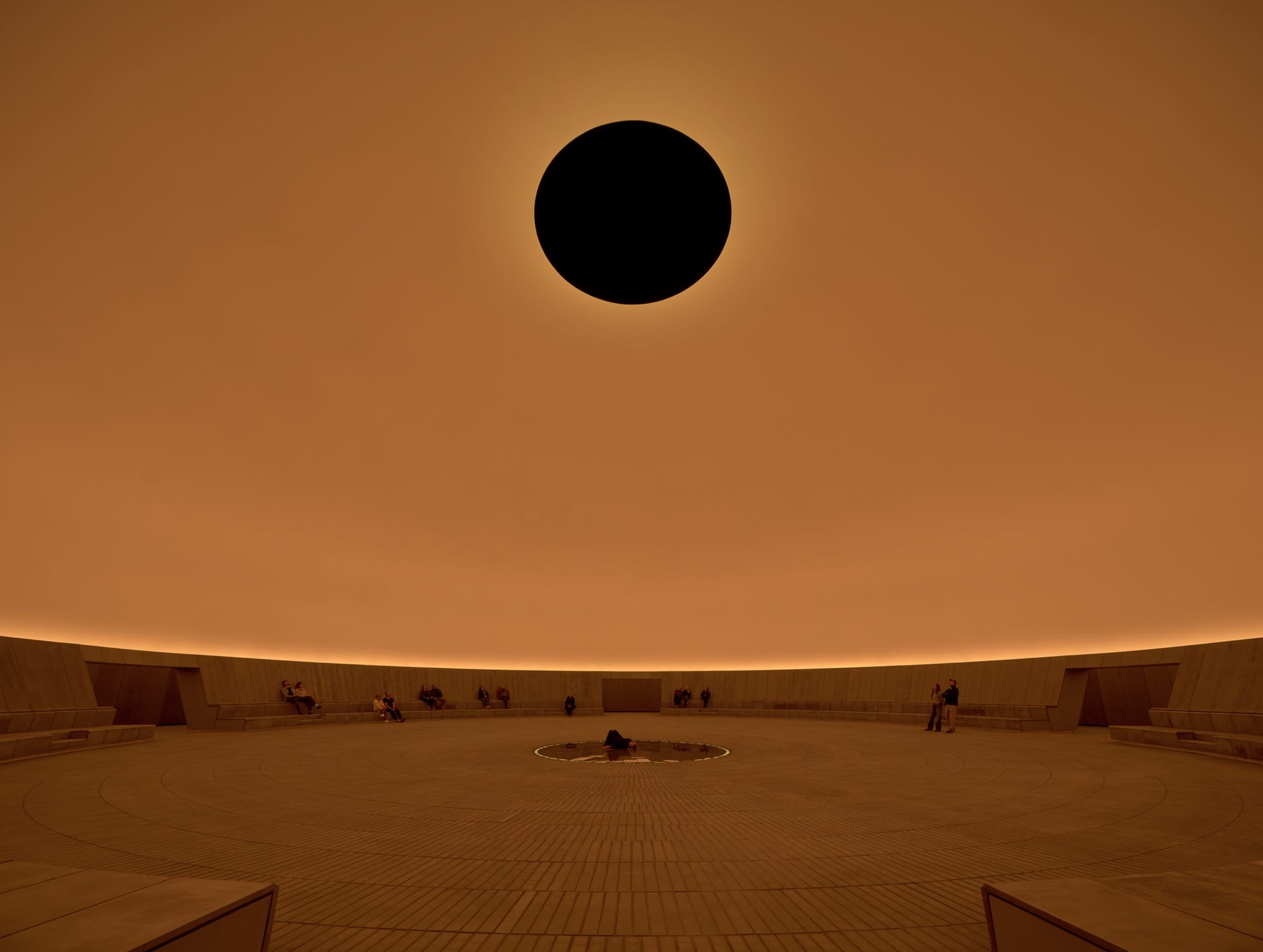James Turrell light installation with a dark oculus in an orange dome