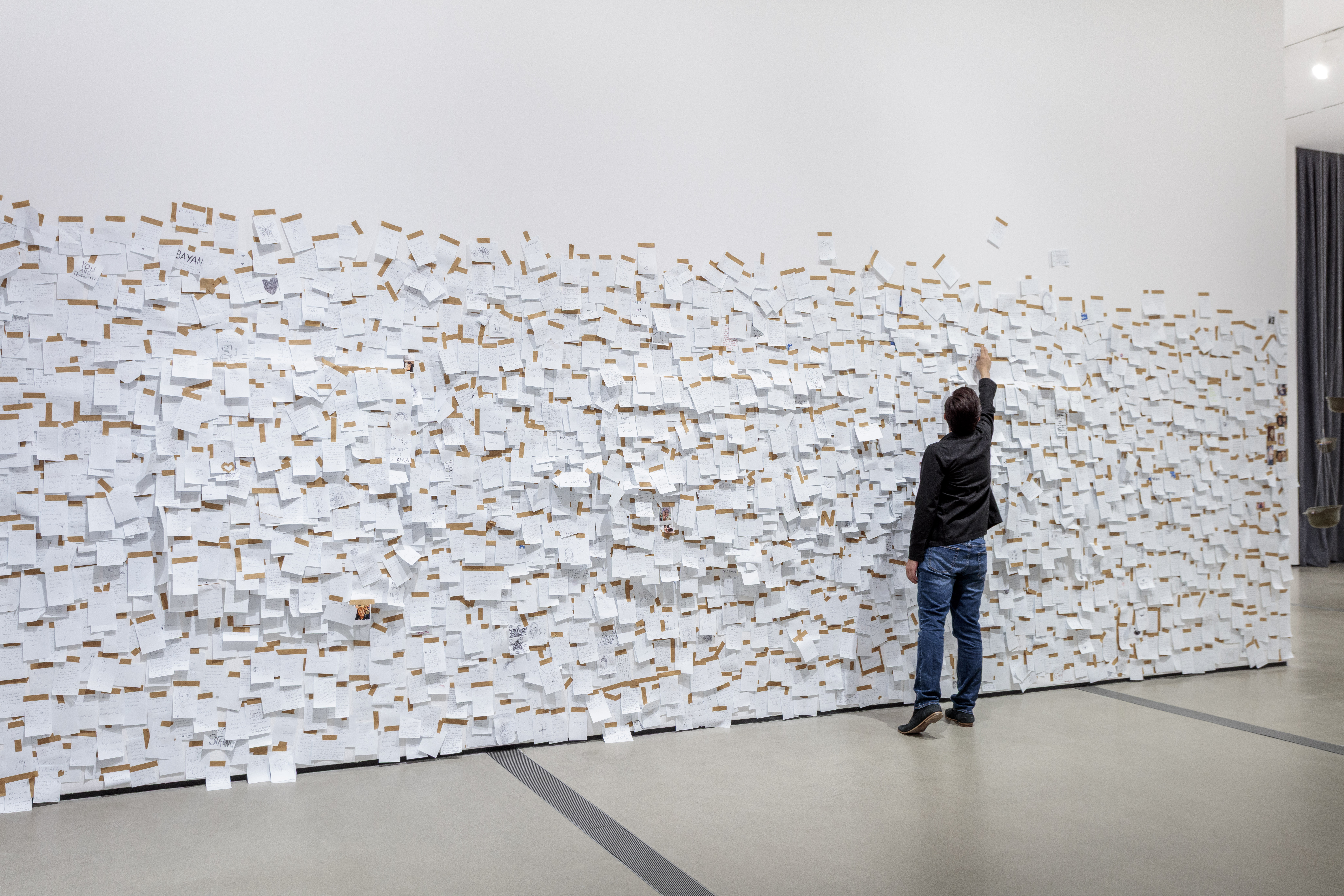 A visitor writing a note for Yoko Ono's My Mommy Is Beautiful