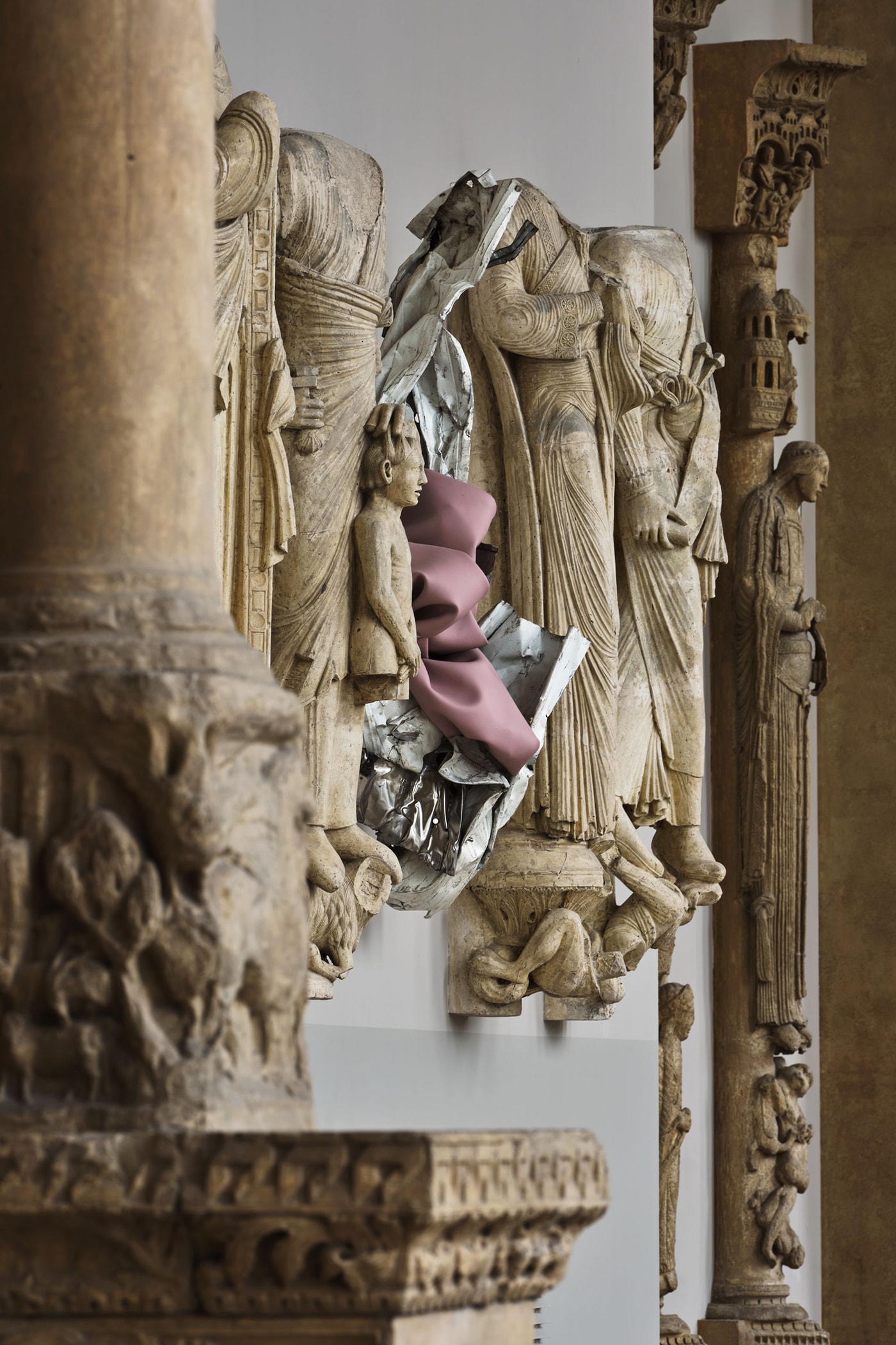 A pink acrylic paint skin and salvaged-metal sculpture by Kennedy Yanko installed among medieval stone figure casts