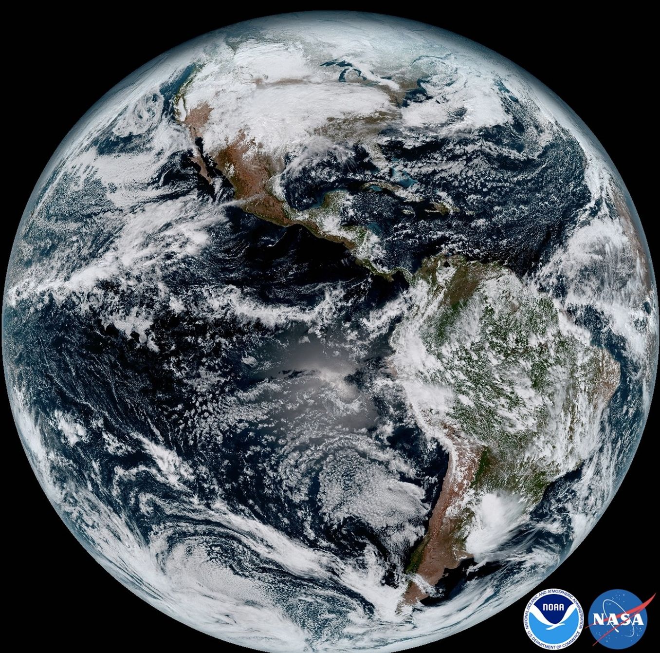 GOES-16 composite view of the Americas and surrounding oceans, with white cloud bands across blue water.