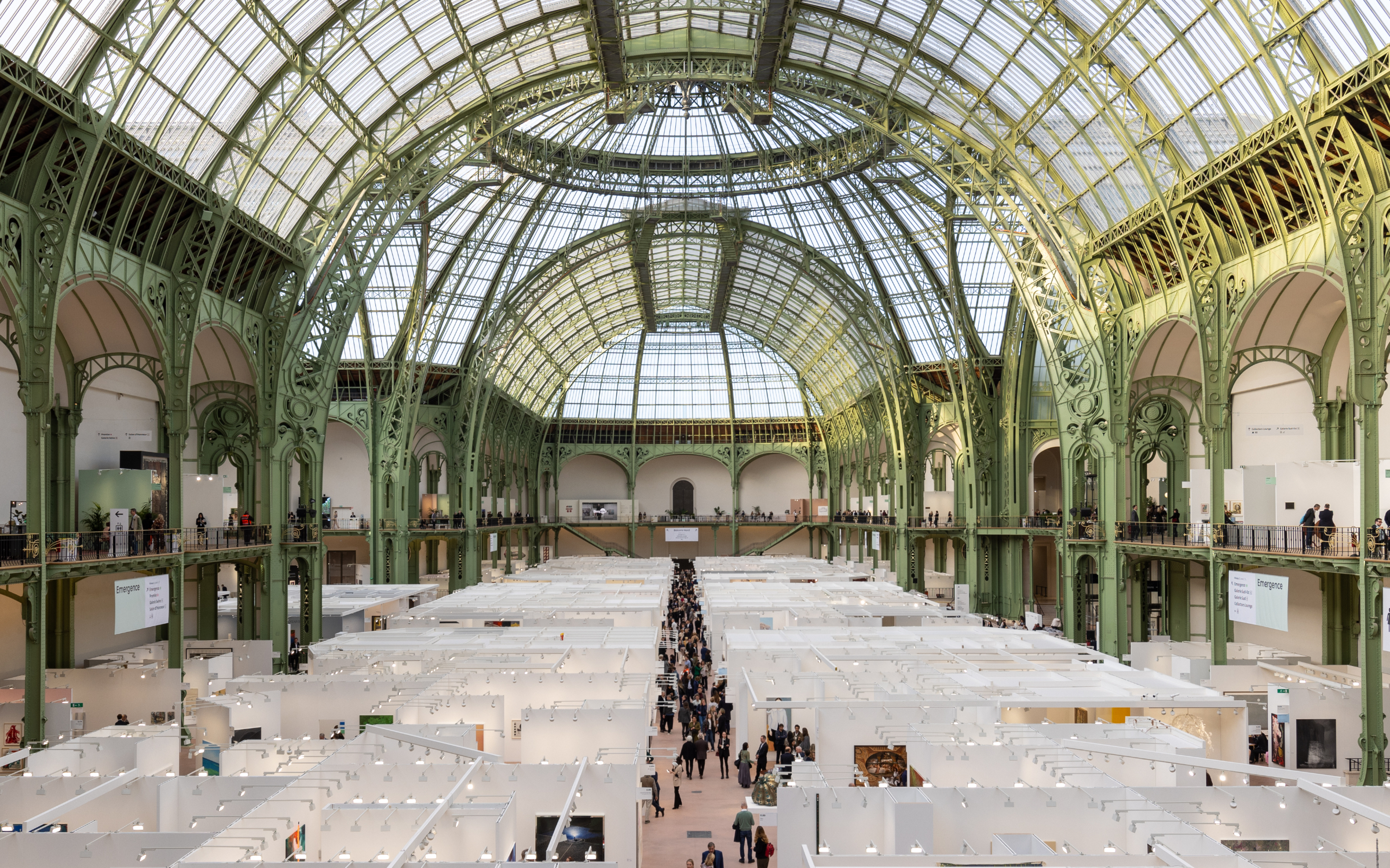 A wide view of Art Basel Paris booths beneath the glass roof of the Grand Palais