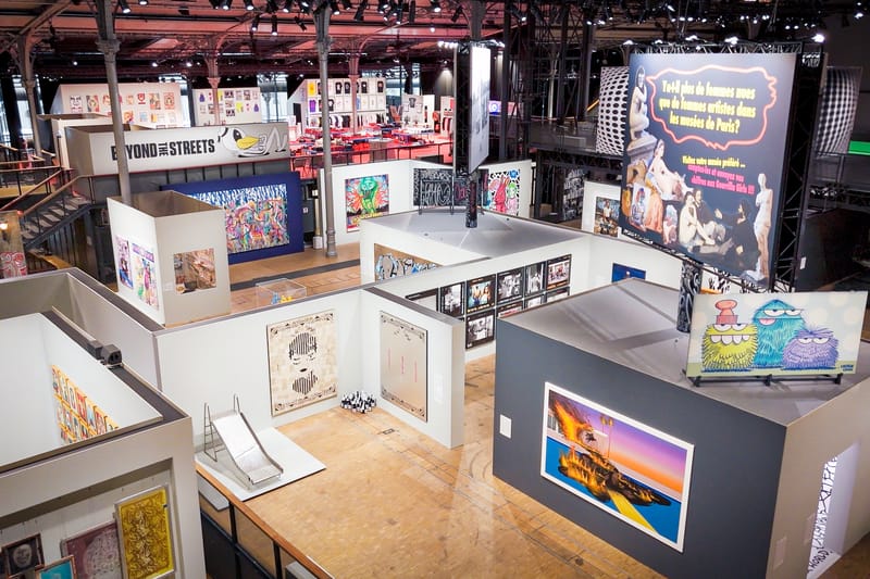 Wide installation view of a BEYOND THE STREETS exhibition filled with paintings, photographs, and graphic works