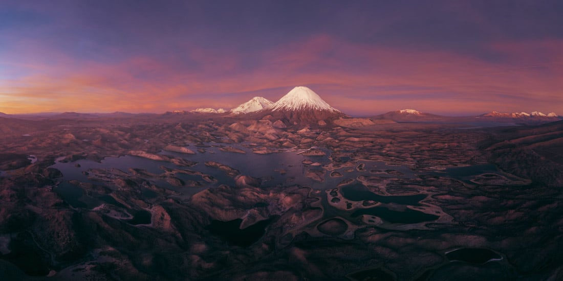 Parinacota and Pomerape volcanoes rise above high-altitude lakes at sunset in Chile